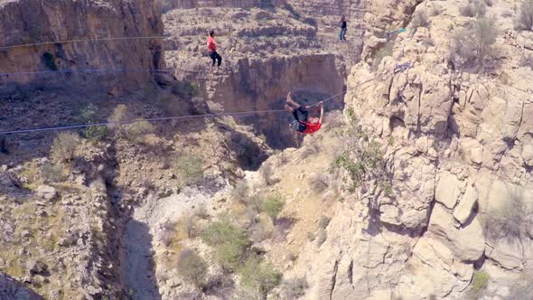 A man balances while tightrope walking and slacklining across a canyon. alt