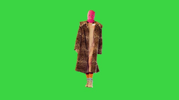 Caucasian Girl in Pink Balaclava and Faux Fur Coat Walks Looking Confident on a Green Screen Chroma