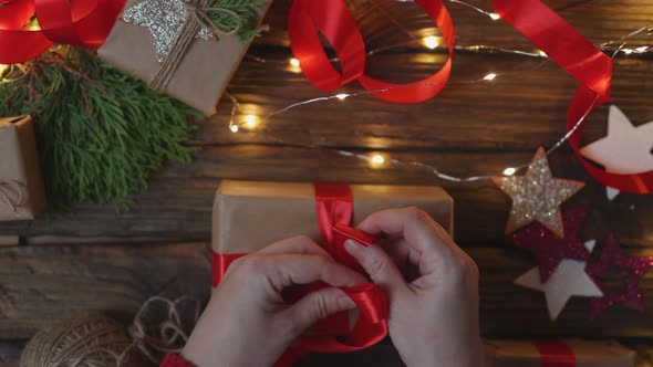 Female Hands Wrapping Christmas Presents Gift Craft Paper Tying Red Ribbon Bow alt