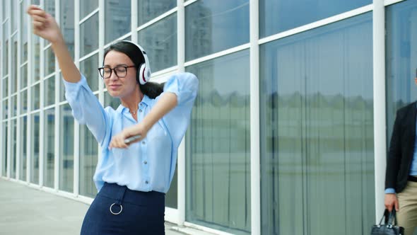 Cheerful Business Lady Dancing Outside Office Center in Street Wearing Headphones alt