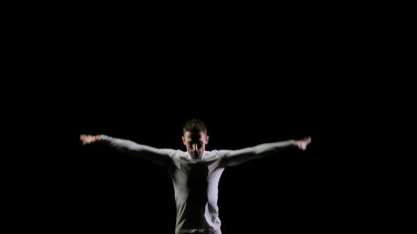 Young Handsome Male Acrobat Gymnast in White Clothes on a Black Background Jumping on a Bot-up and alt