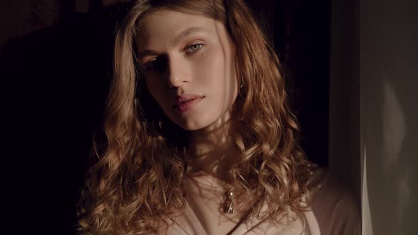 Beautiful European Girl in a Silk Shirt in the Sun Looks at the Camera