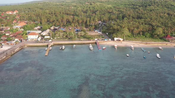 Aerial Shot of Small City with Port on Tropical Island, Sunset with Boats and Ocean at Small Town alt