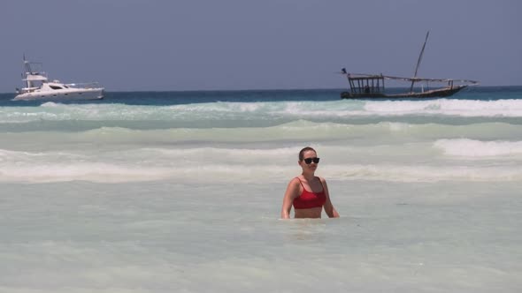 Beautiful Slim Woman in Red Swimsuit Bathes and Rests in Ocean on Paradise Beach alt