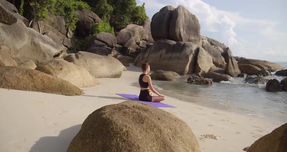 Sport Woman Meditating at Exotic Beach, She Seats on Beach Line Near the Water alt
