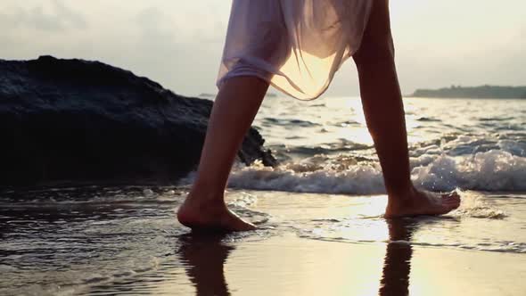 Young woman in white dress walking on beach