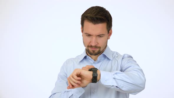 A Young Handsome Man Works on a Touchscreen Wristwatch, Then Smiles at the Camera - White Screen alt