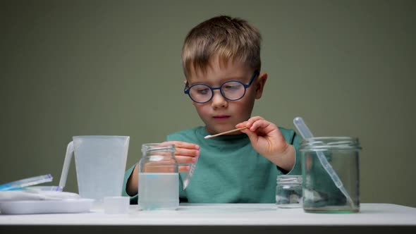 Preschooler Doing Experiment. Young Scientist in Glasses Mixing Up Licquid for Experiments