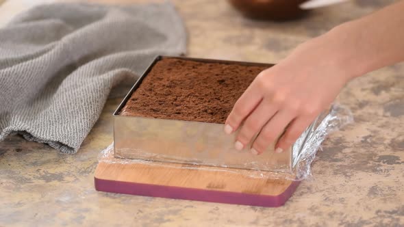 Hands Remove Metal Shape From a Chocolate Cake alt