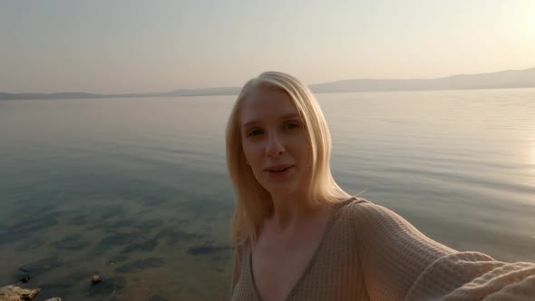Beautiful Blonde Woman Makes Selfie on the Lake