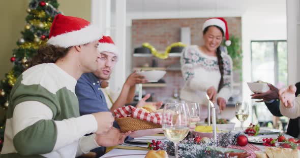 Happy group of diverse friends in santa hats celebrating meal at christmas time alt