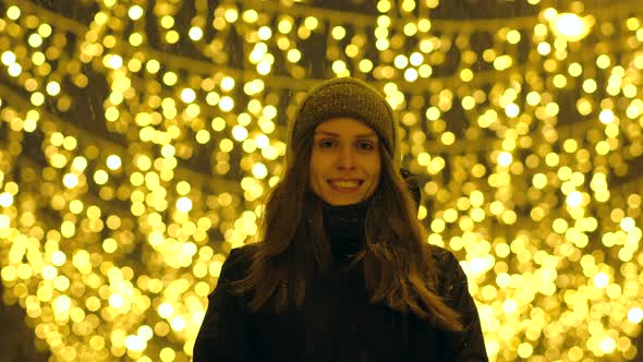 Portrait of a Happy Girl on a Evening Street Decorated with Christmas Lights alt