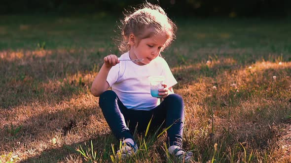 Young Lady Eats Yogurt with Metal Spoon Sitting on Meadow alt