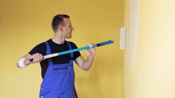 Young man painting wall with roller brush while renovating apartment alt