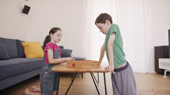 Boy and girl playing a wooden table game at the living room together alt