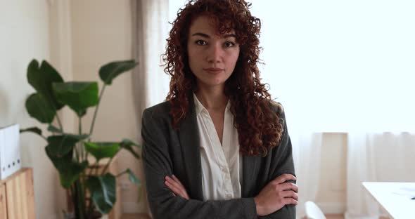 Hispanic young woman looking on camera inside modern office alt