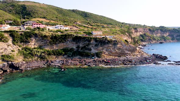Tracking shot aerial drone view of coastline with people sunbathing and relaxing alt