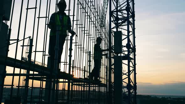 Male Workers Are Walking Along the Building Carcass in Progress alt