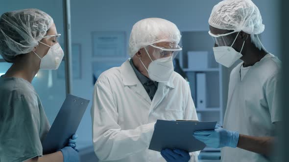 Team of Scientists in Protective Uniforms Discussing Work in Lab alt