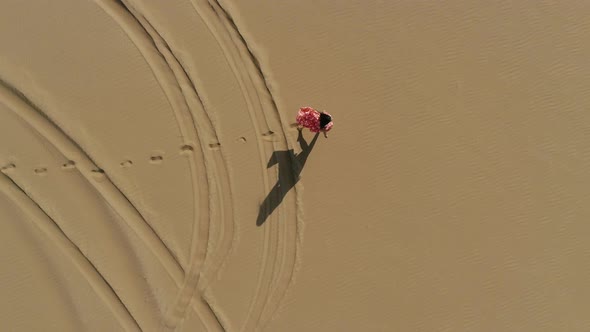 Aerial view of attractive woman walking at a desert landscape, U.A.E. alt