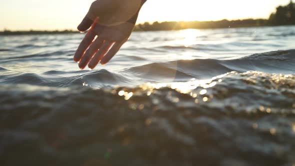 Close Up Woman Hand Gently Touches the Surface of the Water in the Sea
