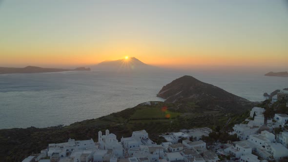 Backwards Pan of White Houses in Plaka Village and Sun Setting Behind Mountain alt