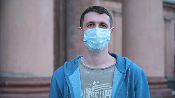 Portrait of a Man on the Streets in the Daytime Wearing a Medical Mask alt