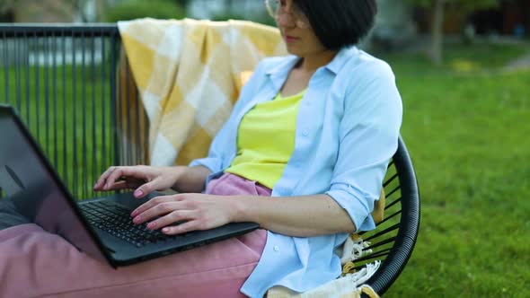 Freelance Woman Works on Laptop at Home in the Backyard