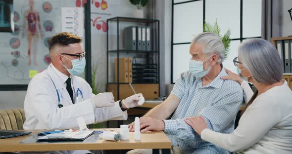 Male Worker Gives an Injection of a Vaccine or Some Medication to a Elder Man in the Clinic alt