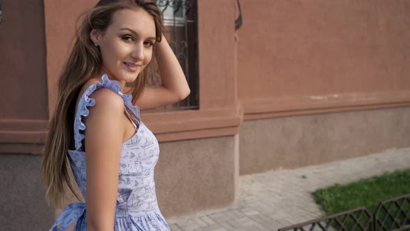 Slim European Model in Trendy Blue Dress Walks Along Street alt