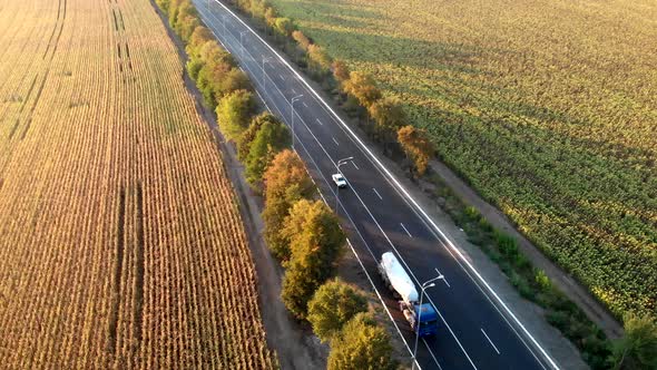 A road with cars between fields. Delivery of goods and logistics