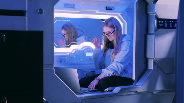 A Girl is Looking Into the Mirror in a Capsule Hotel Room alt