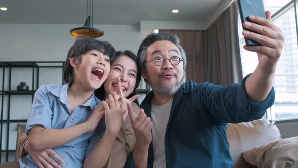 Family smiling at camera. Happy family taking a selfie, smiling at a phone at home. alt