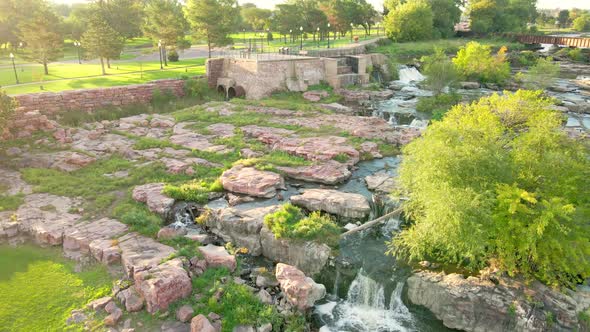 Flyover of part of Falls Park in Sioux Falls, South Dakota with old steel railroad bridge seen.