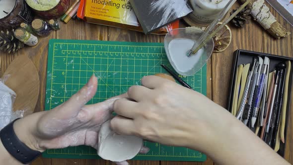 Women's Hands Makes Egg Mold Out of White Clay