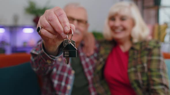 Happy Senior Family Couple Grandparents Man Woman Looking at Camera Demonstrating Keys From New Flat alt