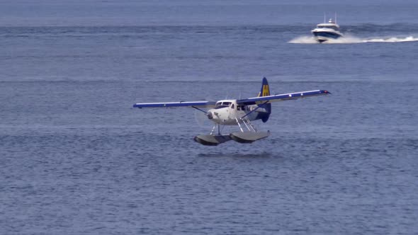 Harbour Air Floatplane Landing In The Burrard Inlet With Sailboat In The Background. - wide alt