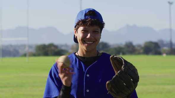 Portrait of happy caucasian female baseball player, on field smiling alt