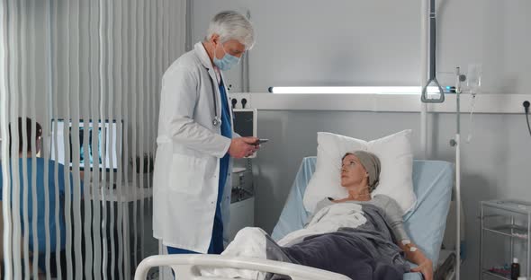 Doctor Telling Results of Medical Tests To Cancer Patient in Hospital Ward alt
