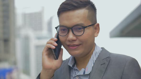 Portrait handsome Asian businessman talking phone with a friend during walking on the urban city.