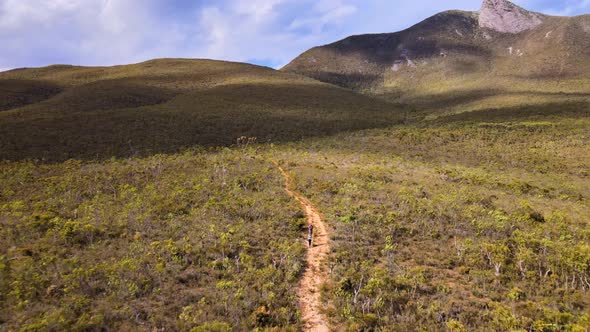 Aerial dolly, hikers follow trail through Australian bush landscape alt