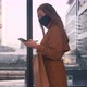 Side View Young Beautiful Business Woman in Face Mask Walks Using Mobile Office App at Mall Window - VideoHive Item for Sale