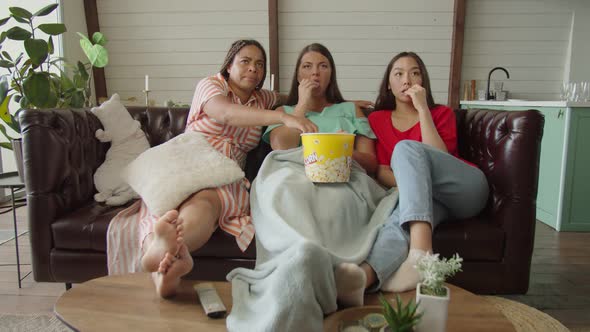 Multiracial Women Expressing Fright By Scary Scene of Film Indoors alt