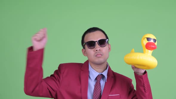 Asian Businessman in Suit with Sunglasses Holding Inflatable Duck Ready To Party alt