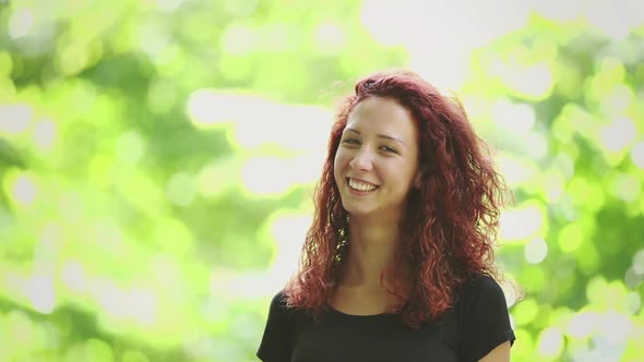 Smiling redhead girl video portrait at park alt