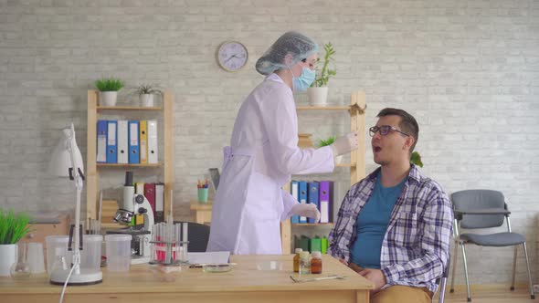 Woman Doctor Taking a Saliva Test From a Man's Mouth with a Cotton Swab alt
