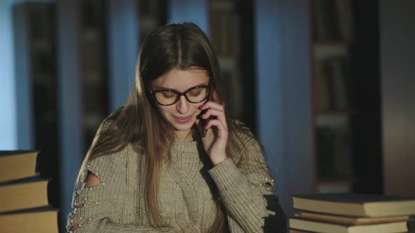 Happy Student Talking on the Mobile Phone When Studying in the Library alt