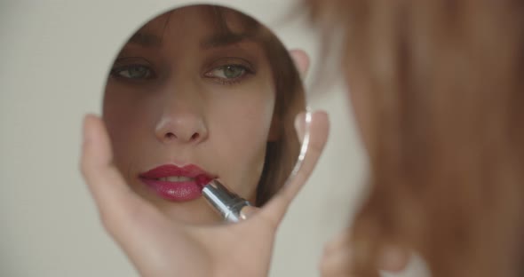 Beautiful Young Woman Holding Mirror To Apply Lipstick