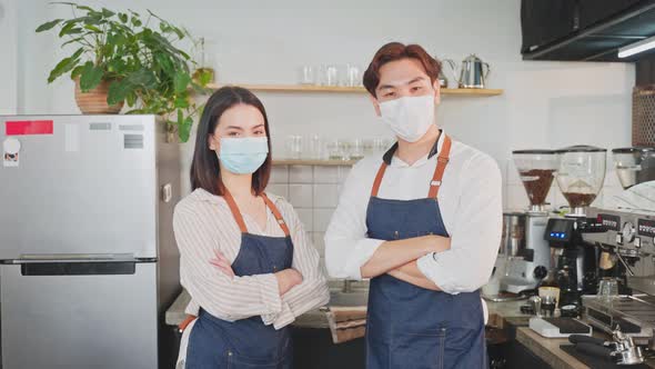 Portrait of young attractive Asian waiter and waitress wearing protective mask due to Covid-19. alt