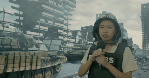 A War Reporter Female Reporting From the Ruined City on the Background of a Passing Convoy of Tanks